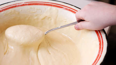 Fresh dough in a large plate and a spoon in the child's hand, foodの写真素材