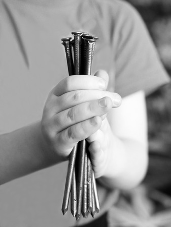 Children's hands hold iron nails, close upの写真素材