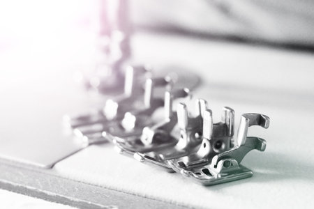 Group of sewing machine accessories. Various presser feet are used for different tasks and stem...