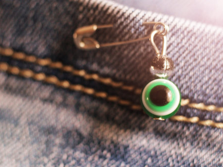 Evil eye on a pin on blue jeansの写真素材