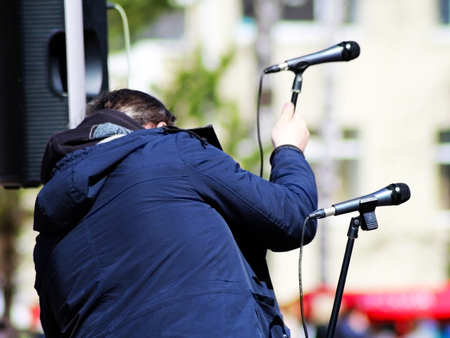 Man sets up a microphone on stage, outdoorの写真素材