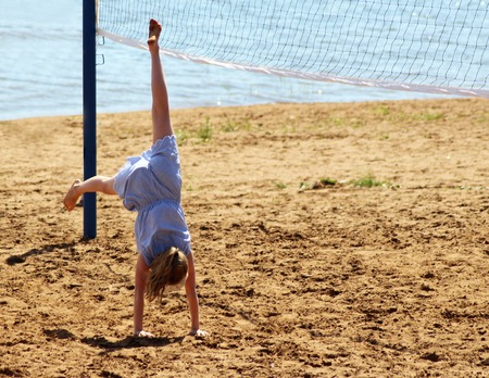 schoolgirl making gymnastics on seashore, nature sunsetの写真素材