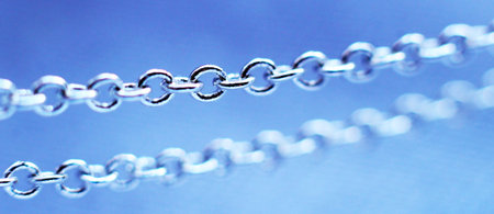 Silver jewelry chain on blue background, macro object