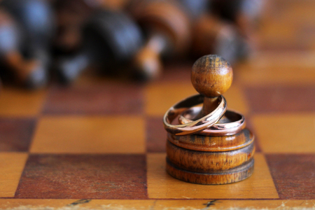 Wedding rings on old wooden chess sp closeの写真素材