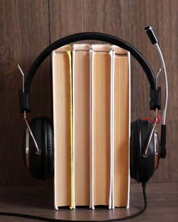 Audio book concept. Headphones and old book over wooden table. Music.の写真素材