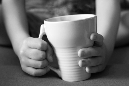 Cup of tea in children's handsの写真素材