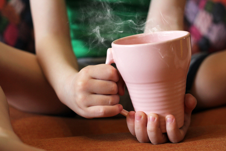 Cup of tea in children's handsの写真素材