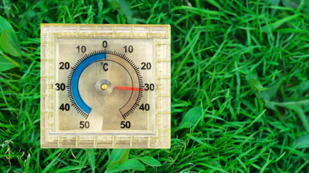 Square thermometer on the grass in the summer