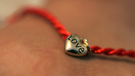 Red thread on hand with a heart of gold, love