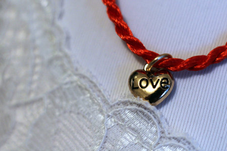 Red thread on hand with a heart of gold, love