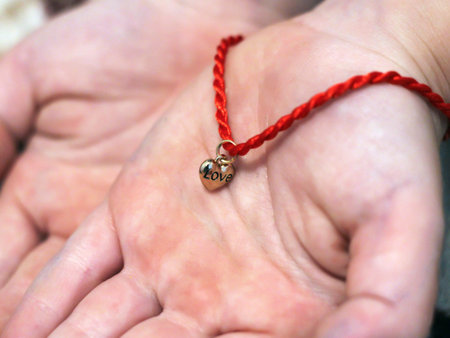 Red thread with a heart of gold on the child's hand so close