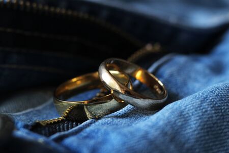 Two gold wedding rings on blue jeans. The concept of love or marriage. So close.の写真素材
