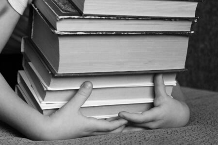 A little boy hugs a stack of books, childの写真素材