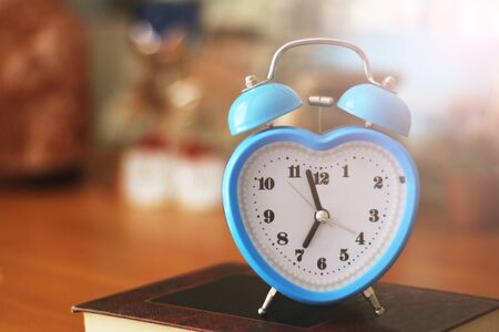 Blue alarm clock in the form of a heart in the interior, tonedの写真素材