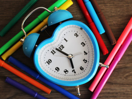 Blue heart-shaped alarm clock and colored markers, object
