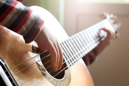 Guitar in the hands of a child of a little girl playing music. People.