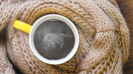 A Cup of hot coffee and a beige warm scarf so close