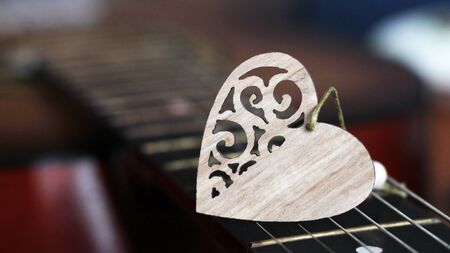 Wooden heart on the strings of the guitar so closeの写真素材