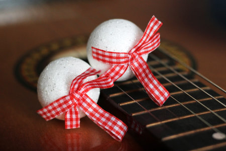 White balls with red bows on guitar so close