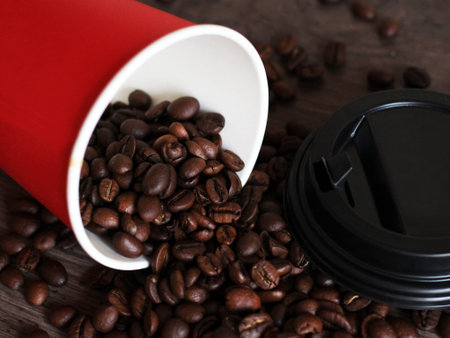 Coffee beans poured from a red plastic Cup so close