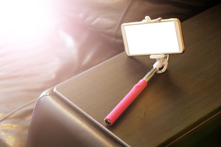 Smartphone on a selfie stick on a leather sofa, toned