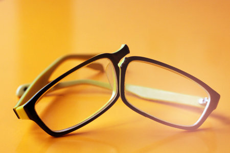 Broken yellow glasses on orange background so close