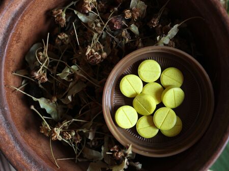 Yellow tablets and medicinal herbs, natural medicine so closeの写真素材