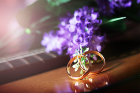 Wedding rings on the cords of the guitar and purple flowers so closeの写真素材