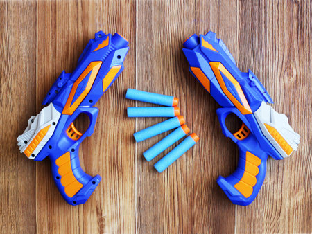 Blue pistol and cartridges on wooden background, toy for a boy