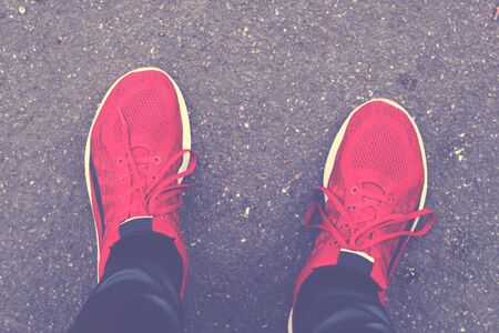 young man feet in red sneakers on a road top viewの写真素材