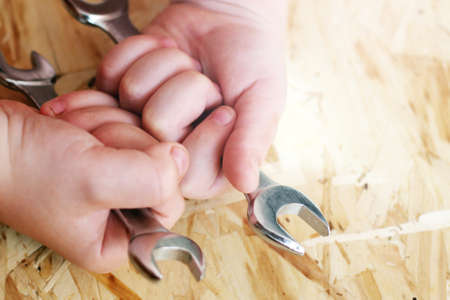 The hand hold a spanner on a wooden backgroundの写真素材