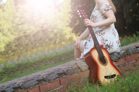 Beautiful girl and retro guitar in the garden, outdoor