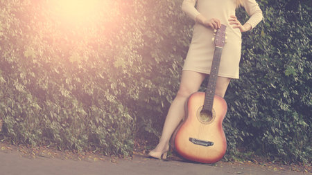 Beautiful girl and retro guitar in the garden, outdoor