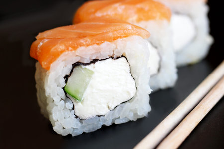 Seafood. Traditional sushi and rolls on the dish. Black background.