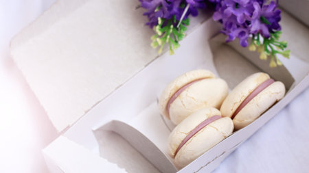White macaroons in a cardboard box, dessert. Sunlight toned.