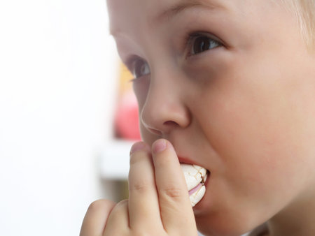 Little boy eats white macaroons so close