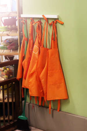 Orange aprons on a hanger, sunlightの写真素材