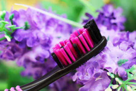 Black and pink toothbrush with purple flowers. Healthcare object.の写真素材
