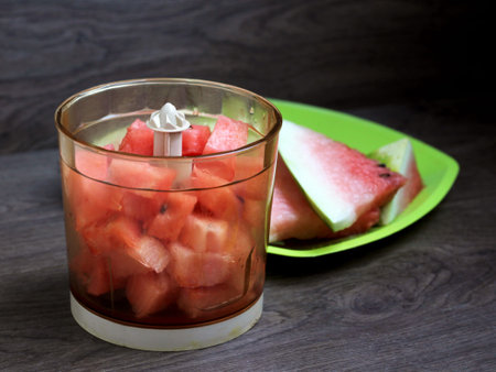 Ripe watermelon slices in a blender, wooden backgroundの写真素材