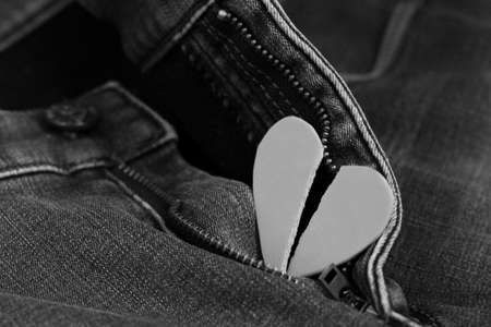 Black heart ripped in half on jeans, black and white imageの写真素材
