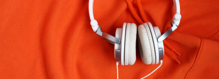White headphones on orange background, music