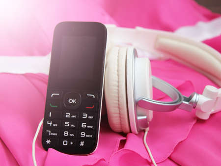 White headphones with mobile phone on pink dressの写真素材