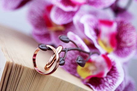 bouquet of pink flowers, wedding rings and a book so close