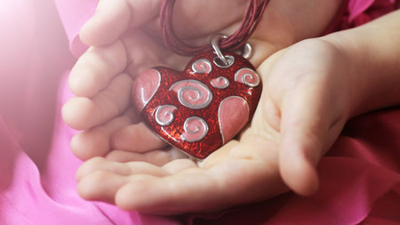 Heart decoration in children's hands, pink background