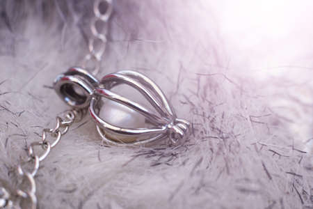 Silver pendant with pearls on a chain, gray background, light tonedの写真素材