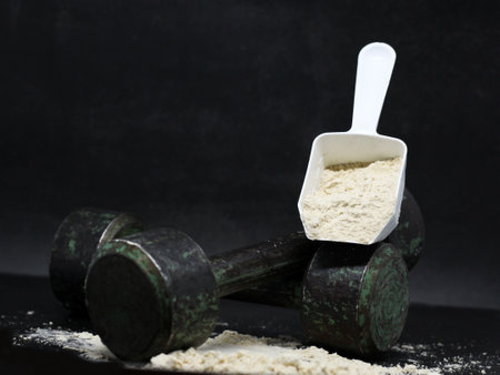 Dry protein in a spoon and old iron dumbbells. Sport.の写真素材