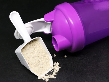 Whey protein powder and purple plastic shaker on a black table