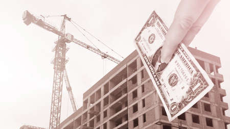 Construction crane and building, money for construction, dollar in hand.の写真素材
