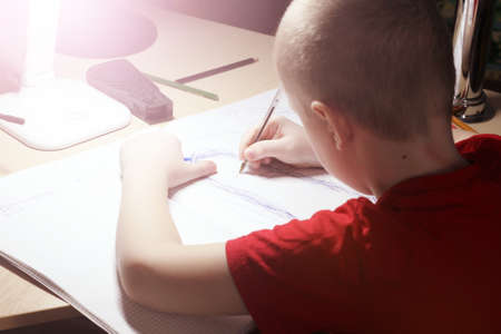Portrait of a young boy writing in the room so closeの写真素材