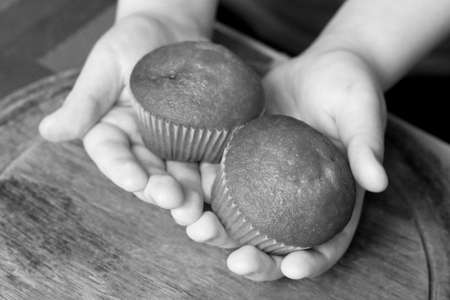 Two muffins in children's hands, sweet food, black and whiteの写真素材